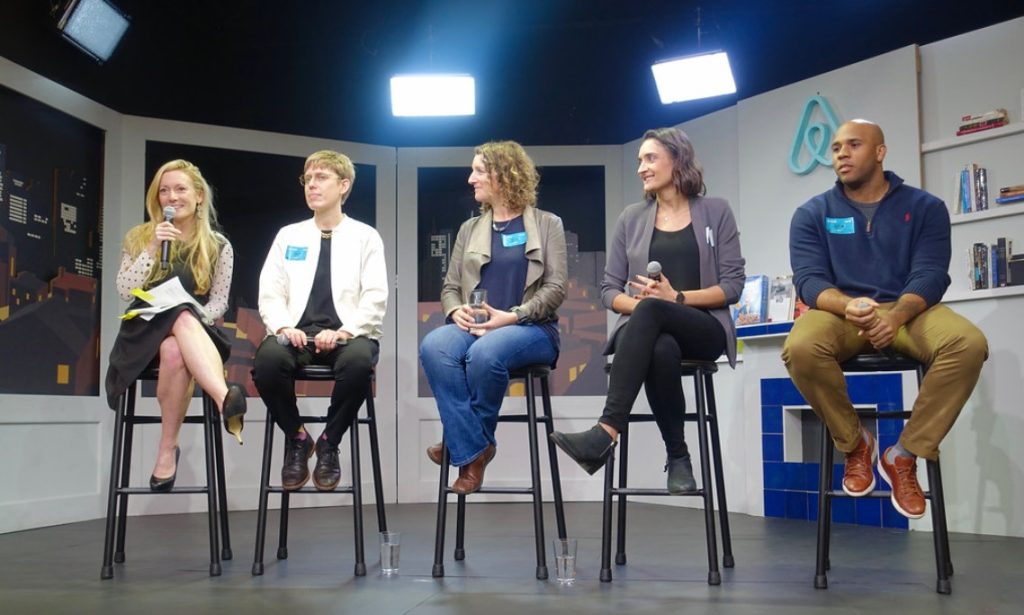 a woman speaks into microphone while others listen